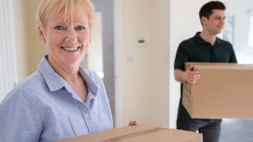 middle aged woman and adult son moving boxes into new house