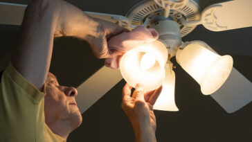 man cleaning decorative light fitting
