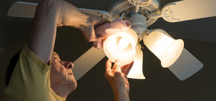 man cleaning decorative light fitting