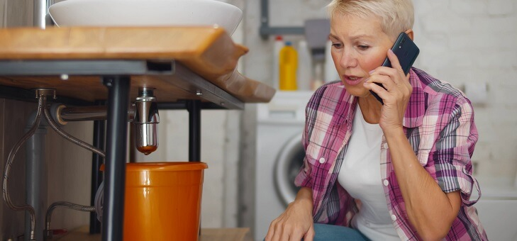 woman on phone to plumber while looking at sink