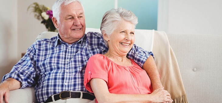 happy retired couple relaxing on couch