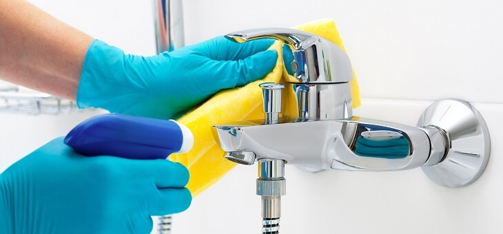 hands wearing rubber gloves wiping bathroom surfaces