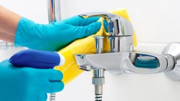 hands wearing rubber gloves wiping bathroom surfaces