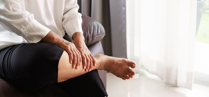 woman rubbing leg to relieve cramp