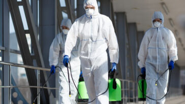 health workers in full protective gear spraying disinfectant