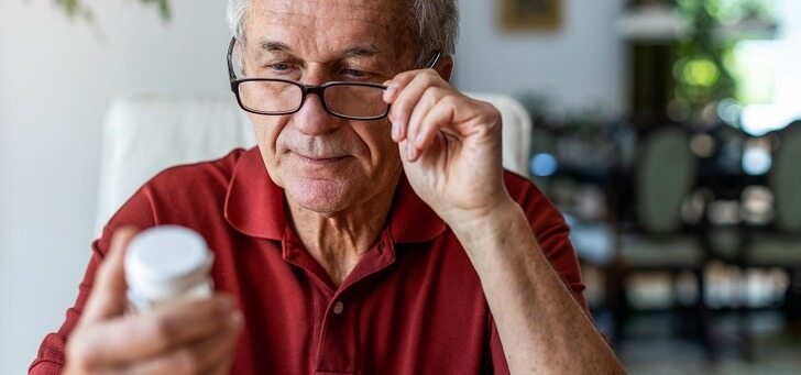 senior man straining eyes to read medicine label