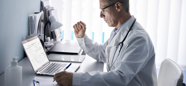 doctor reading patient record on laptop