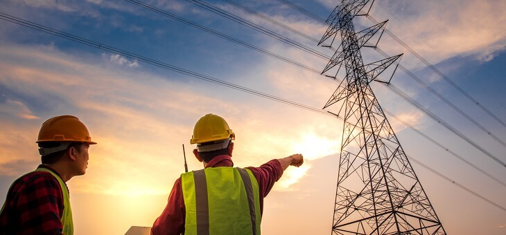 electrical workers looking at power transmission tower