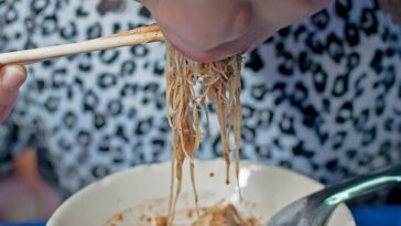 woman slurping noodles from bowl