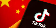 person looking at TikTok on phone in front of Chinese flag