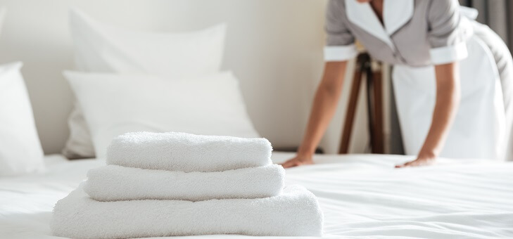 maid making bed in hotel room