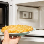 woman taking eggs from microwave