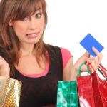 guilty looking woman holding shopping bags and credit card