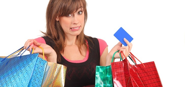 guilty looking woman holding shopping bags and credit card