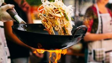 man stir-frying noodles in wok