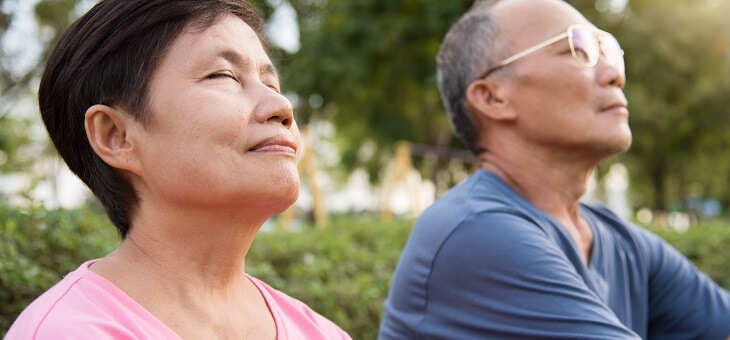 mature couple doing breathing exercises in the park