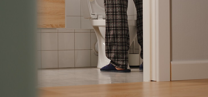 feet of man urinating in toilet
