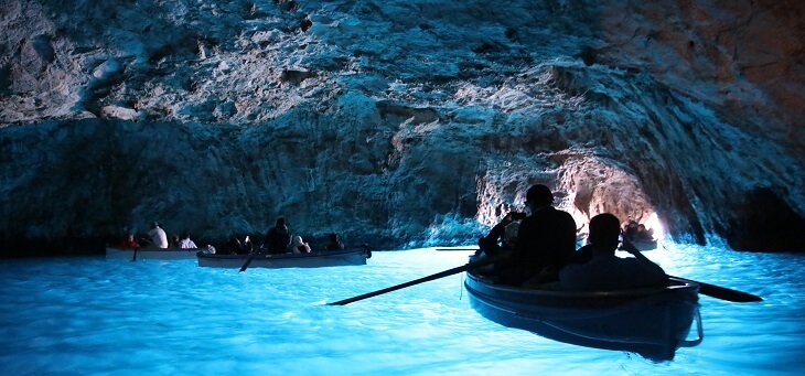 tourists in canoe going through Italian grottos