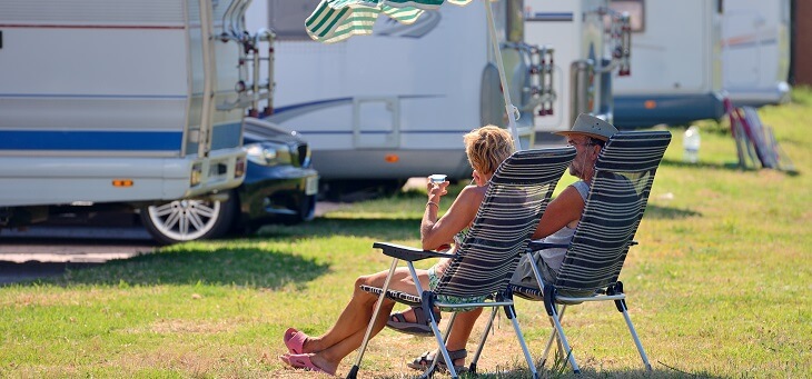 older couple sitting outside caravan