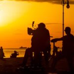 film crew filming on beach at sunset