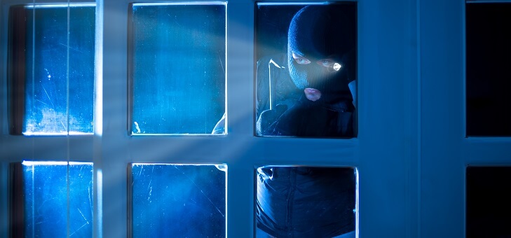masked burglar looking through window, home safety