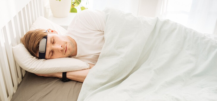 man in bed wearing brain monitoring device