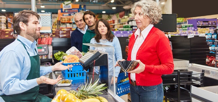 woman at checkout who is struggling pay grocery bills