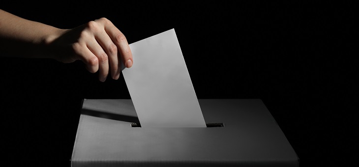woman placing voting form in ballot box