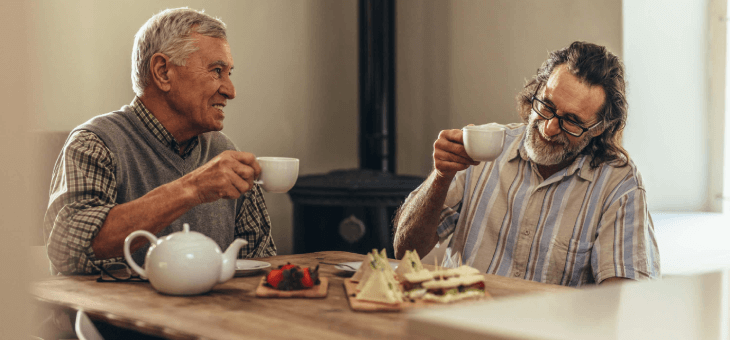 Two men sharing a cup of tea and biscuits