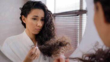 Woman looking in the mirror at her damaged hair
