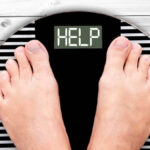 Feet on weighing scales displaying the word 'help'
