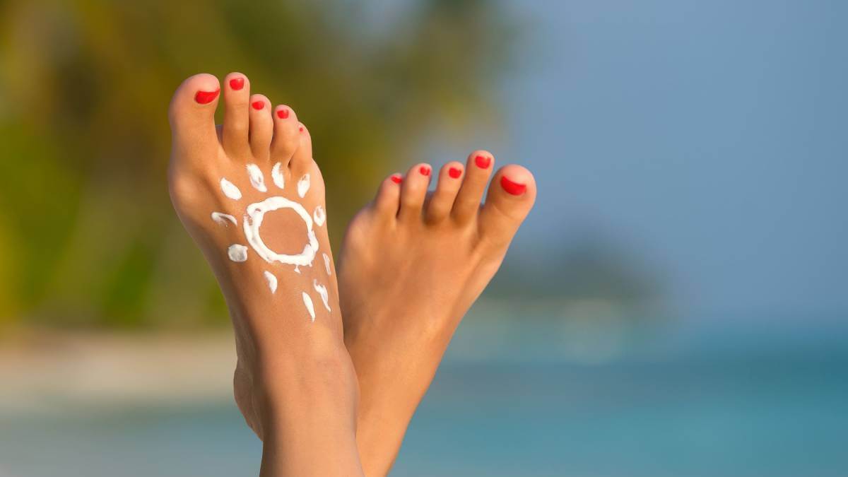 Feet in the air with a sun drawn on in suncream