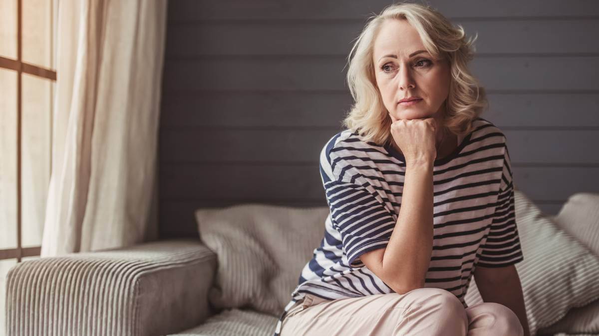 Woman sitting alone on sofa looking worried