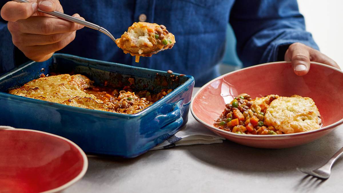 A comforting cottage pie being served from a blue baking dish