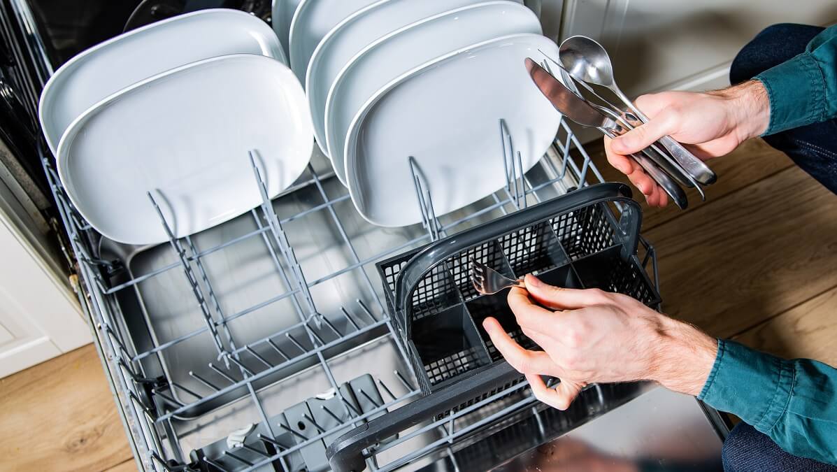man stacking cutlery in dishwasher