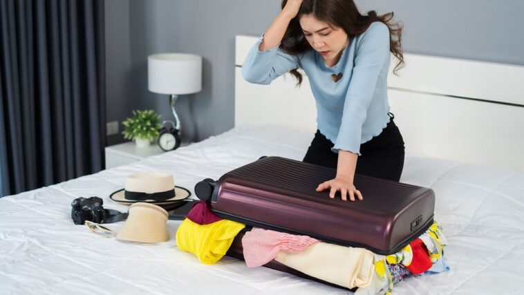 woman over packing suitcase