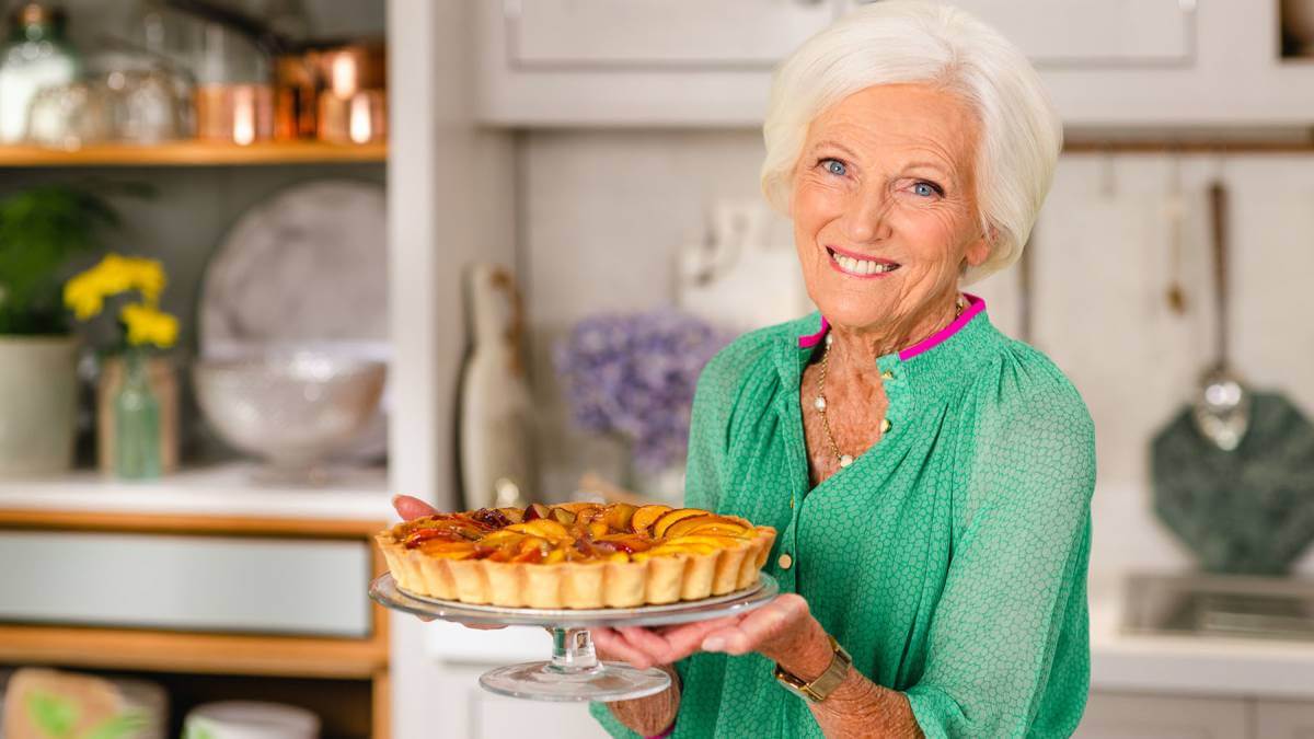 Mary Berry holding up a pie in a glass dish