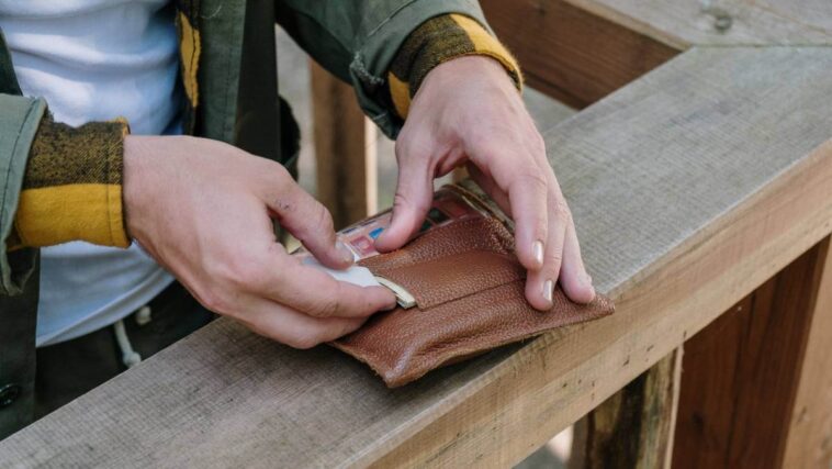 Man's hands putting cash in wallet