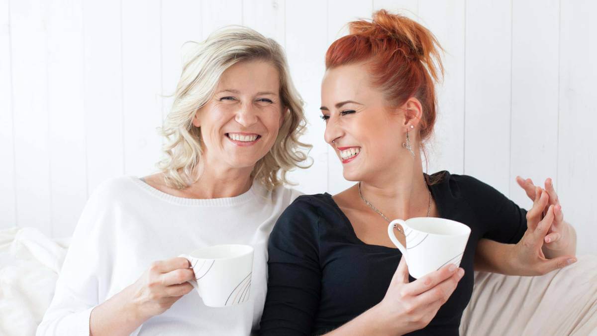 Mum and daughter both holding a cup of tea