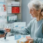 older woman using her commonwealth seniors health card at the pharmacy