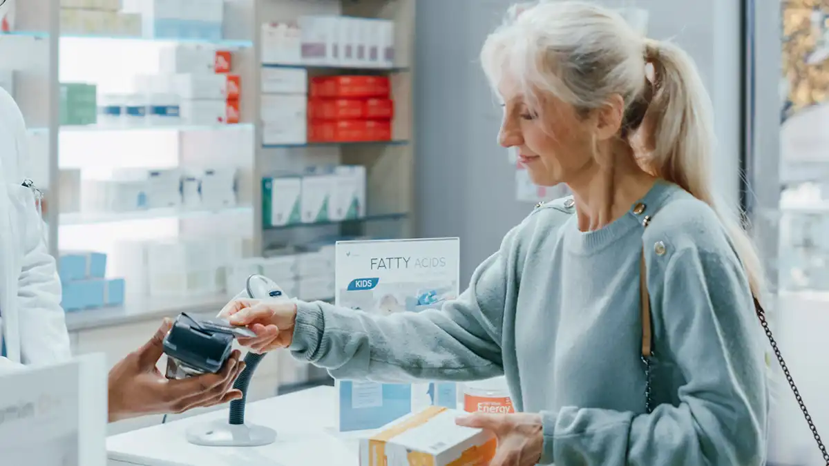 older woman using her commonwealth seniors health card at the pharmacy
