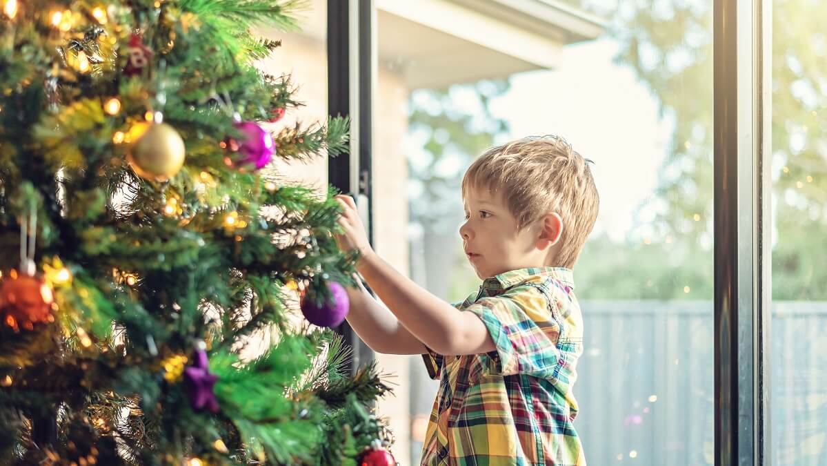little boy decorating christmas trees