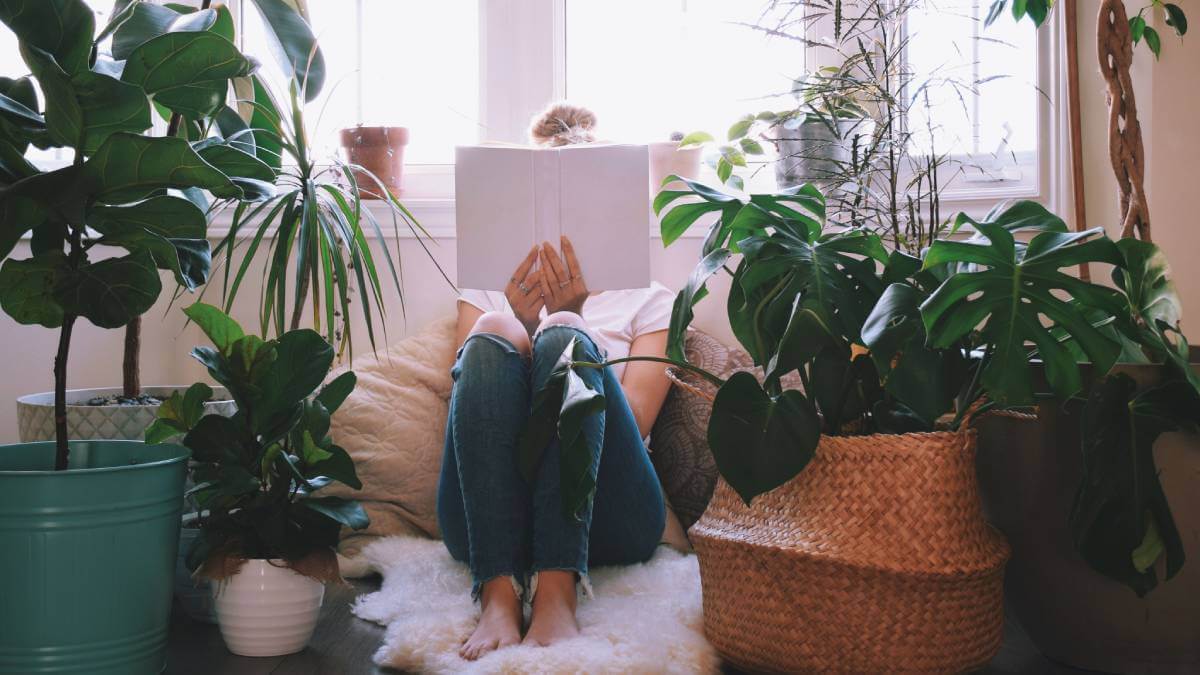 Woman reading in a little nook filled with plants