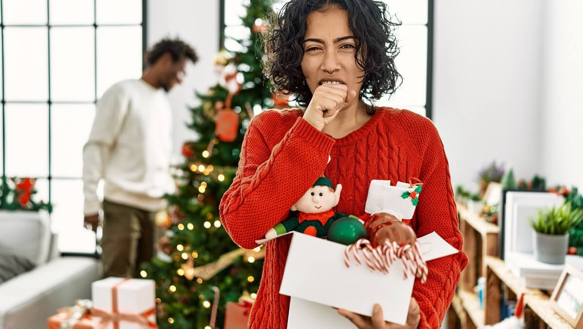 woman coughing in front of christmas tree