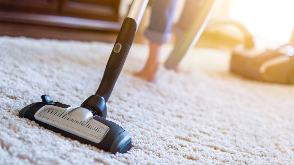 Vacuum being pushed along a white rug
