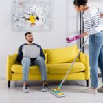 woman cleaning mess while man sits