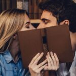 Man and woman hiding their faces behind a book