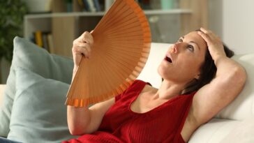woman cooling herself with fan