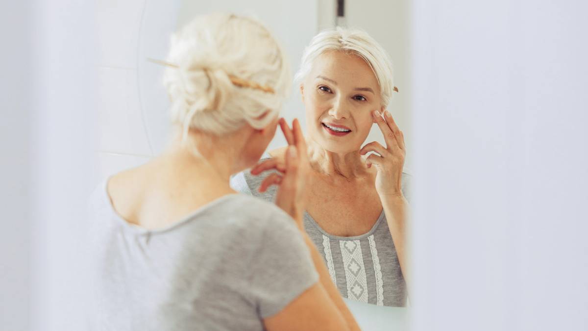 Woman looking at her skin in the bathroom mirror