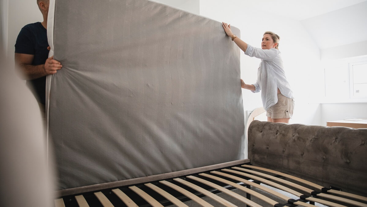couple placing new mattress on bed